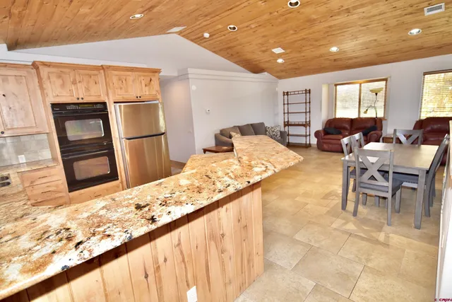 a living room with stainless steel appliances kitchen island granite countertop furniture a refrigerator and wooden floor