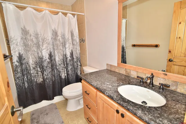 a bathroom with a granite countertop sink toilet and a mirror