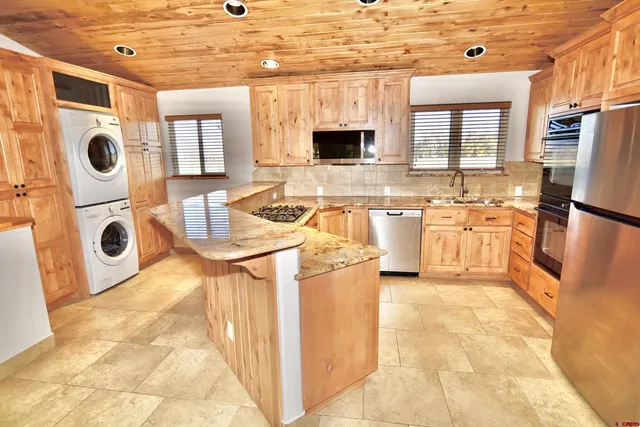 a large kitchen with stainless steel appliances granite countertop a sink and cabinets