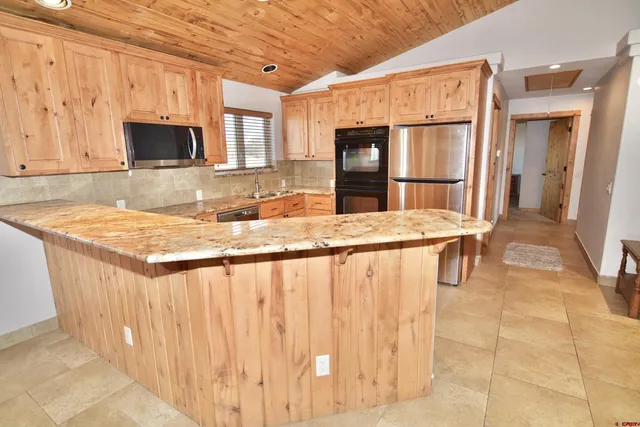 a kitchen with stainless steel appliances granite countertop a sink refrigerator and cabinets