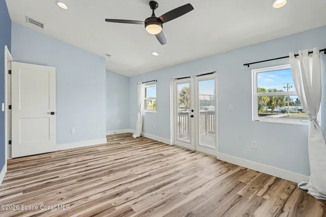 a view of an empty room with window and wooden floor