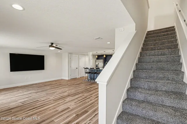 a view of a livingroom with wooden floor and staircase
