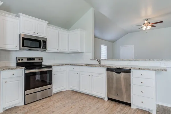 an empty room with a chandelier fan and windows