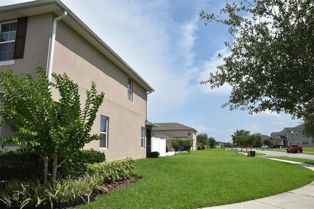 a view of a house with brick walls and a yard with plants