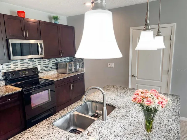 a kitchen with stainless steel appliances granite countertop a stove a sink and a microwave