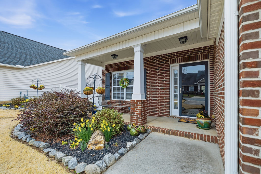This inviting home features a classic brick exterior with a welcoming porch and vibrant landscaping.