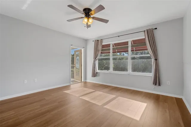 a view of a big room with wooden floor and a chandelier fan in a room