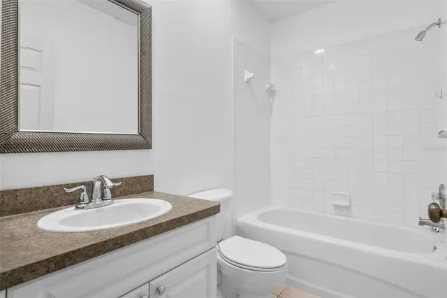 a bathroom with a granite countertop toilet a sink and bathtub