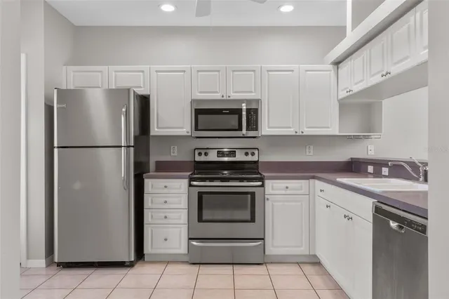 a kitchen with granite countertop a refrigerator and a stove top oven