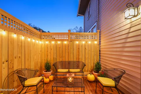 a view of a patio with table and chairs with wooden floor and fence