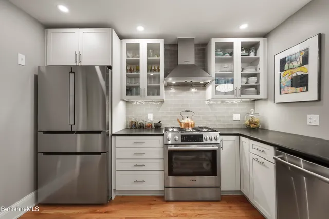 a kitchen with stainless steel appliances granite countertop a refrigerator and a stove top oven