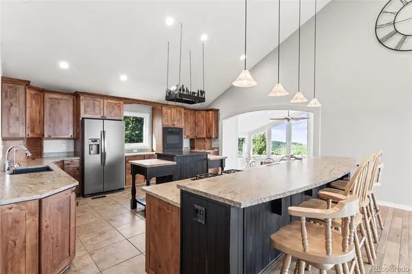 a kitchen with stainless steel appliances granite countertop a sink a stove a refrigerator cabinets and chairs