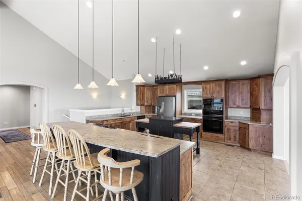 a kitchen with stainless steel appliances kitchen island granite countertop a table chairs sink and cabinets