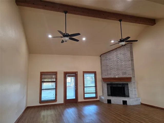 a view of an empty room with a fireplace and wooden floor