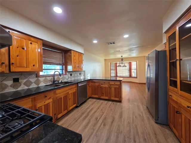 a kitchen with stainless steel appliances granite countertop wooden floors a stove and a sink