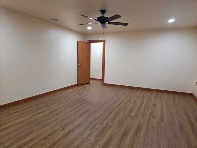 a view of an empty room with window and wooden floor