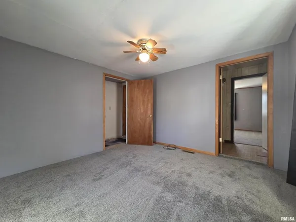 a view of an empty room with window and chandelier fan