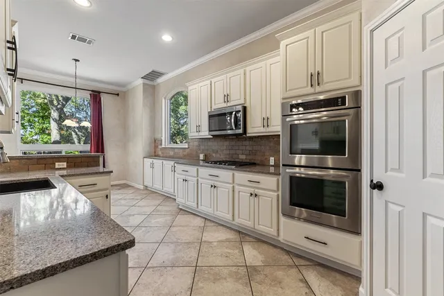 a kitchen with stainless steel appliances granite countertop a stove a sink and a microwave