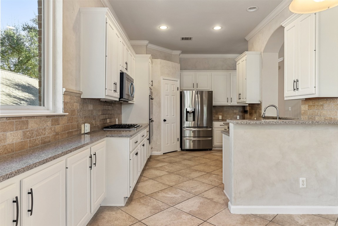 2932 Grimes Ranch Road Austin, TX 78732 - Photo 28 of 38 a kitchen with stainless steel appliances granite countertop a refrigerator sink and white cabinets