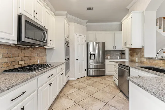 a kitchen with stainless steel appliances granite countertop a stove a sink and a microwave