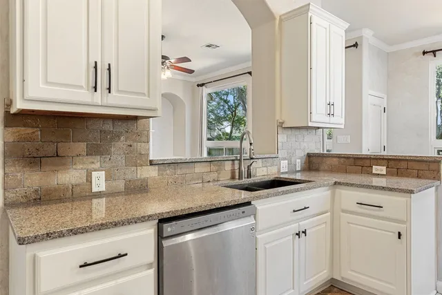 a kitchen with stainless steel appliances granite countertop a sink dishwasher and white cabinets with wooden floor
