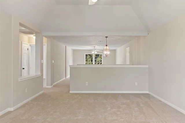 an empty room with kitchen view and wooden floor