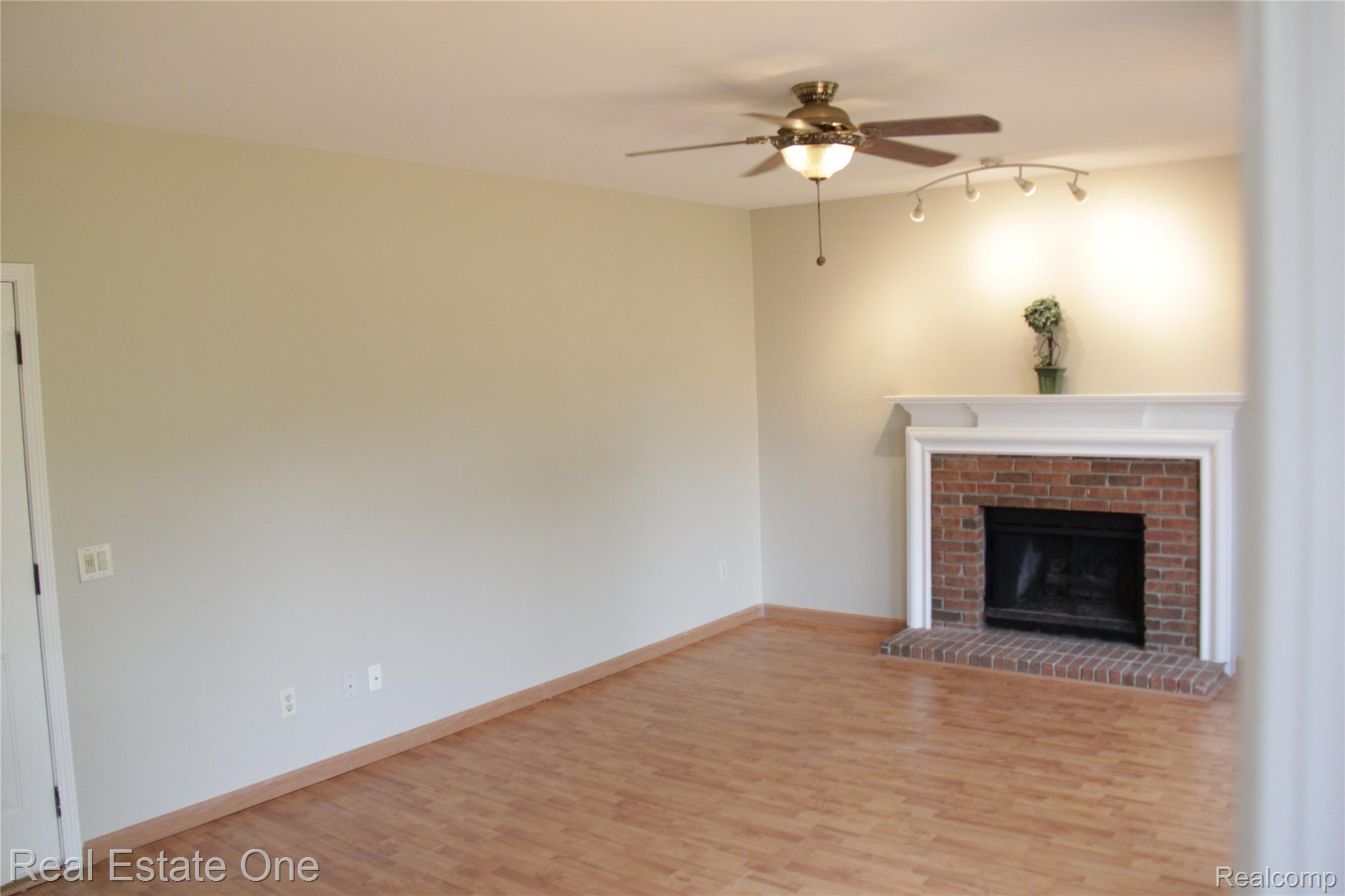 44777 Saltz Road Canton, MI 48187 - Photo 28 of 65 Spacious Family room featuring wood-finish flooring, a brick fireplace with a white mantel, track lighting, and a ceiling fan with integrated lighting