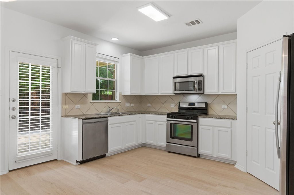 14815 Avery Ranch Boulevard, Unit 302 Austin, TX 78717 - Photo 7 of 30 a kitchen with granite countertop stainless steel appliances a stove sink and microwave