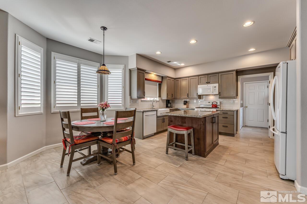 10650 Silver Cliff Way Reno, NV 89521 - Photo 9 of 38 a kitchen with stainless steel appliances kitchen island granite countertop a table chairs sink and cabinets