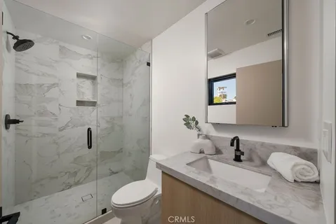 a bathroom with a granite countertop sink a toilet a mirror and shower