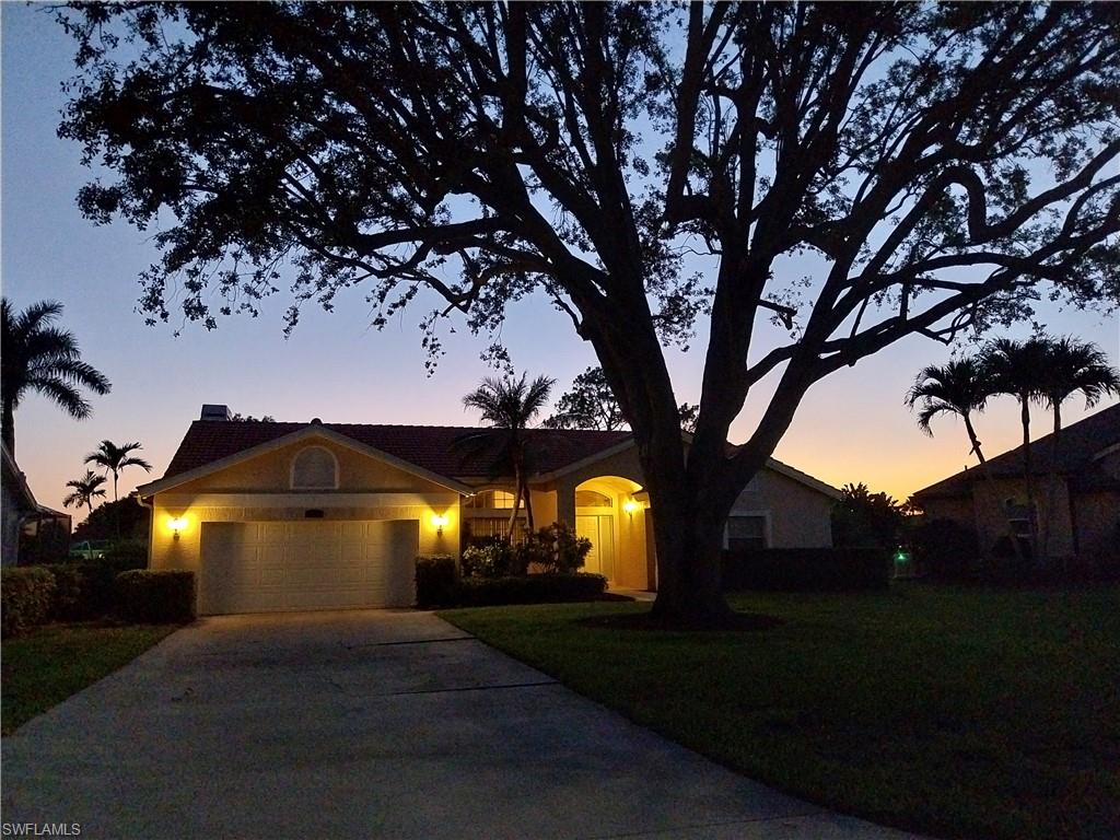 449 Dundee Court Naples, FL 34104 - Photo 2 of 35 Ranch-style house featuring an attached garage, driveway, a front yard, and stucco siding