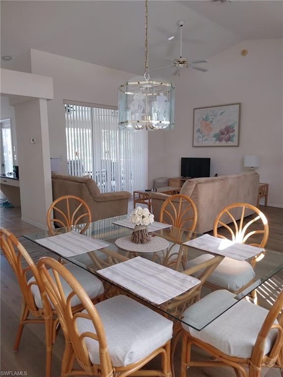 449 Dundee Court Naples, FL 34104 - Photo 7 of 35 Dining space featuring wood finished floors, vaulted ceiling, and a ceiling fan
