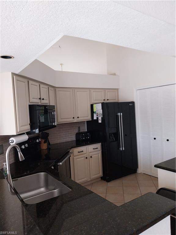 449 Dundee Court Naples, FL 34104 - Photo 10 of 35 Kitchen featuring fridge, backsplash, light tile patterned flooring, a textured ceiling, and range