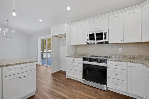 a kitchen with granite countertop white cabinets white stainless steel appliances and wooden floor