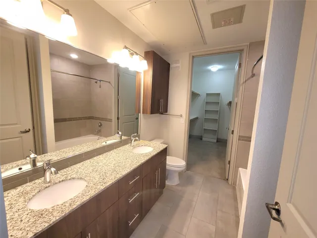 a bathroom with a granite countertop double vanity sink and mirror