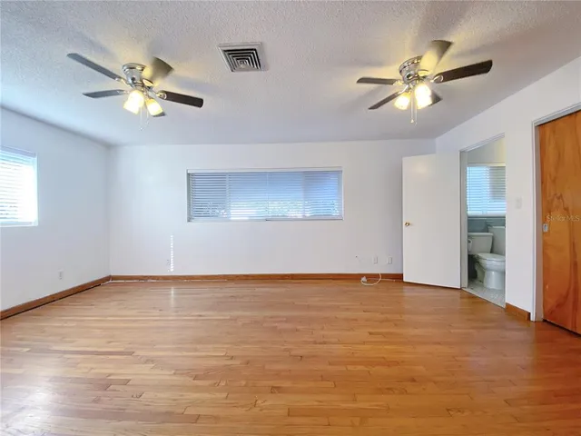 a view of an empty room with window and a kitchen