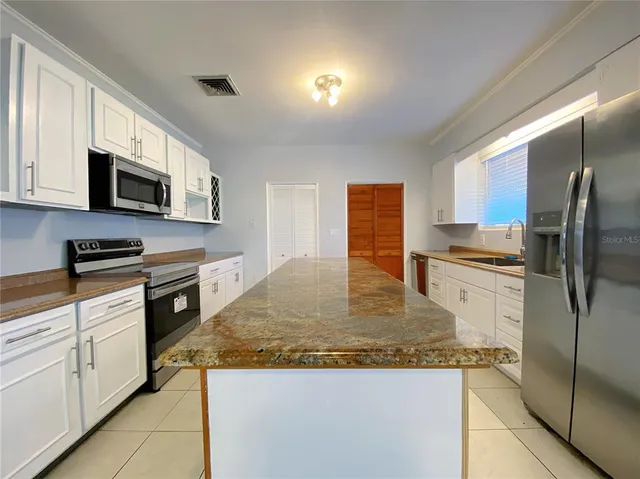 a kitchen with stainless steel appliances granite countertop a stove a sink and a microwave