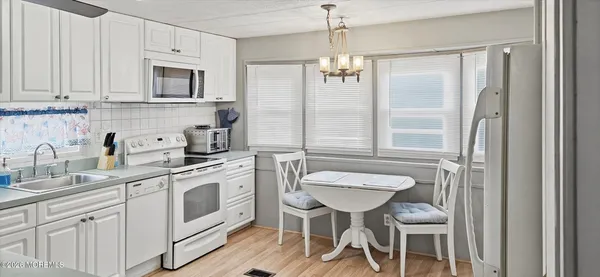 a kitchen with stainless steel appliances a white table chairs and a refrigerator