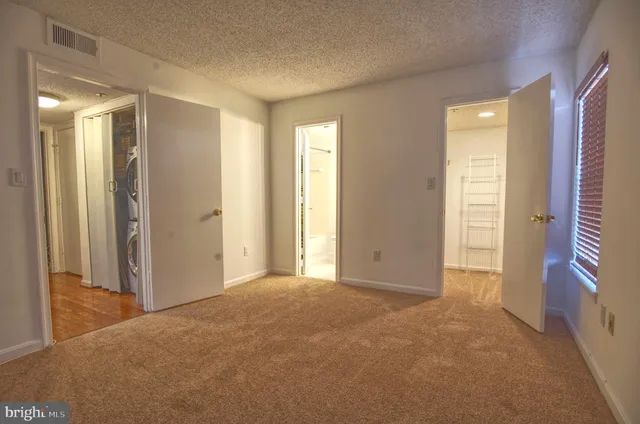 a view of an empty room with window and a bathroom