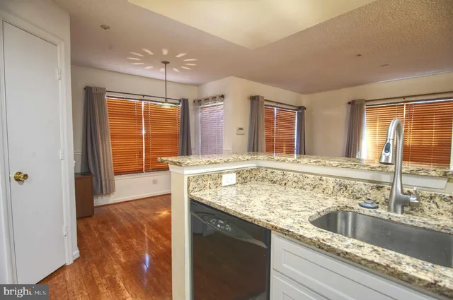 a kitchen with stainless steel appliances granite countertop a sink a stove and a wooden cabinets