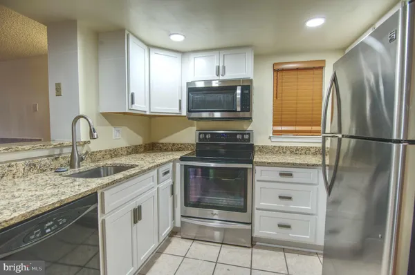 a kitchen with granite countertop a refrigerator stove and microwave