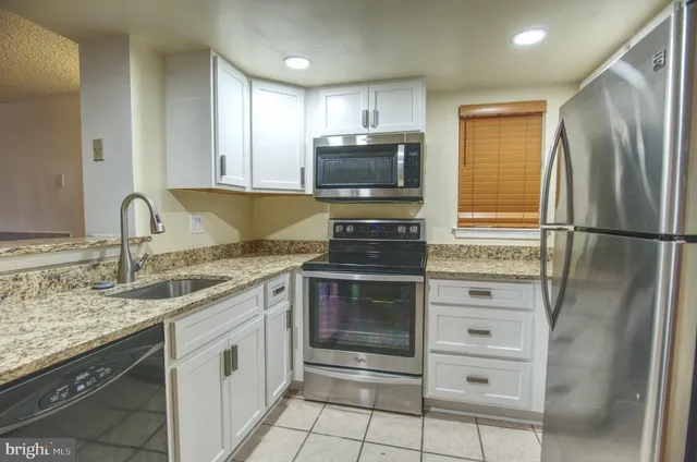 a kitchen with granite countertop a refrigerator stove and microwave