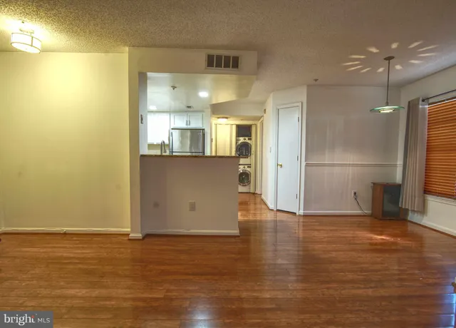 a view of a kitchen with wooden floor and a refrigerator