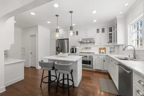 a kitchen with kitchen island granite countertop a sink cabinets and wooden floor
