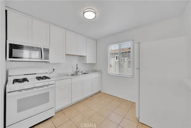 a kitchen with granite countertop white cabinets and white appliances