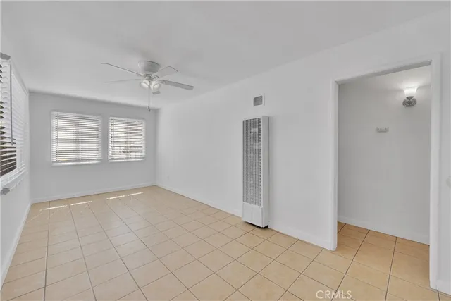 a view of an empty room with window and chandelier fan