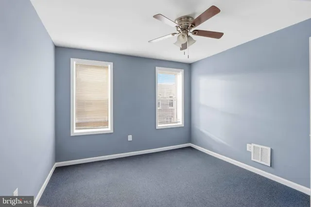 an empty room with a window and a fan