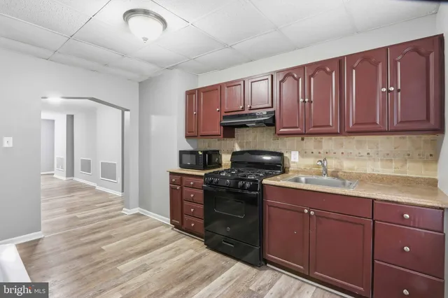 a kitchen with stainless steel appliances granite countertop a stove a sink dishwasher and a refrigerator with wooden cabinets