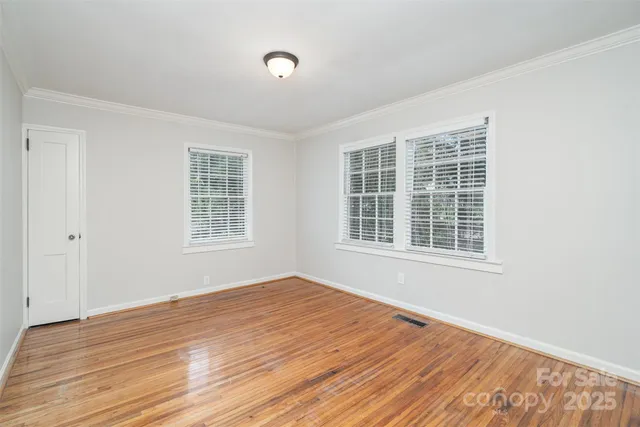 a view of an empty room with wooden floor and windows
