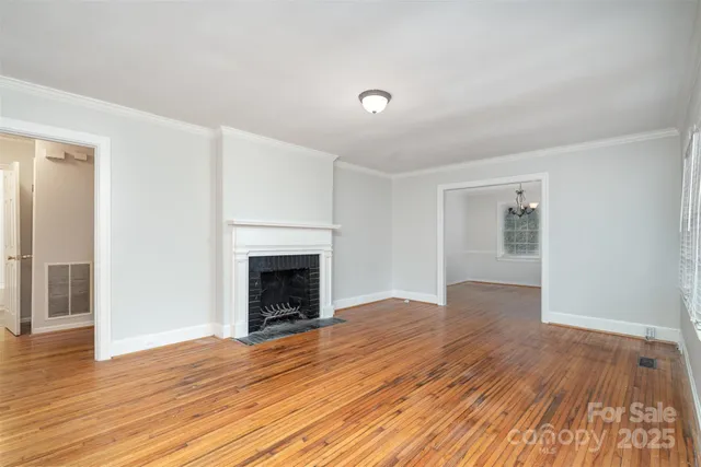 an empty room with wooden floor fireplace and windows